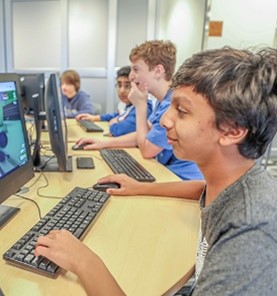 Four boys sitting using desktop computers