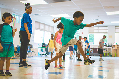 A group of children in a classroom jumping from square to square
