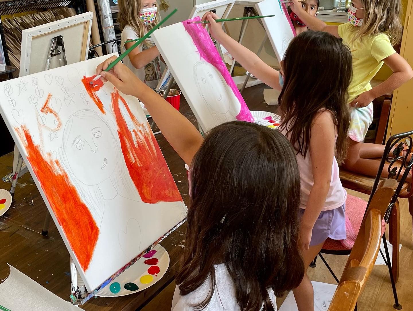 Multiple girls painting portraits on a canvas