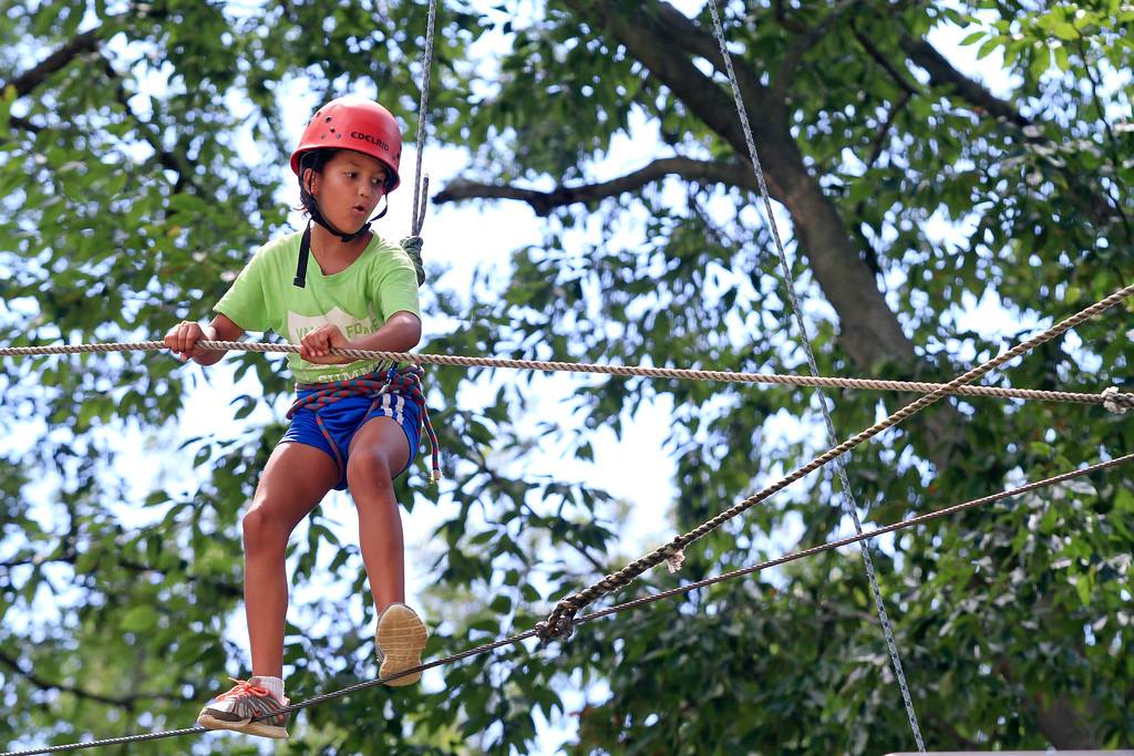 A girl wearing a red helmet doing high ropes